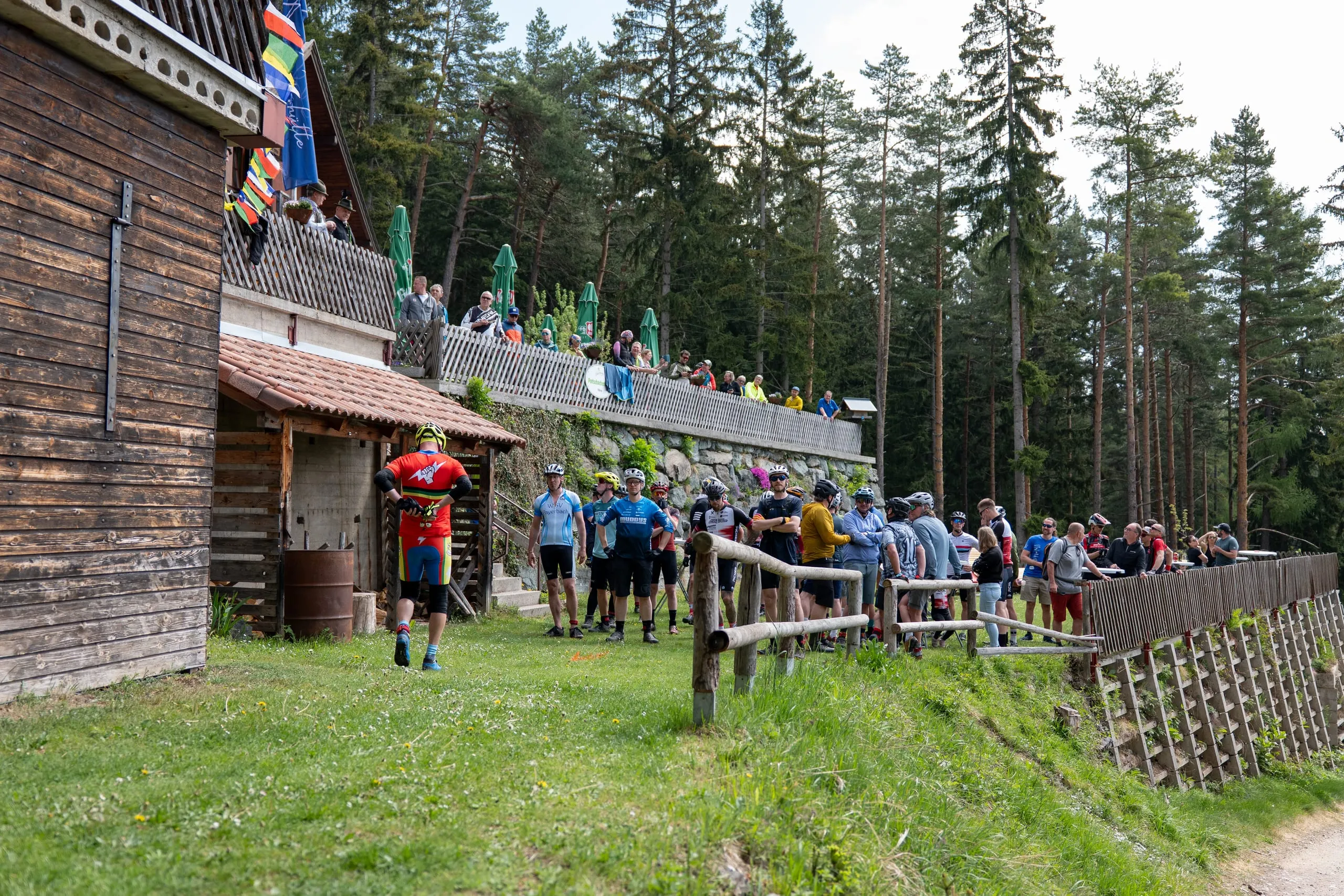 Vor der Holzfassade der Pottschacherhütte sammelt sich das Starterfeld, Zuschauer auf der Terrasse darüber