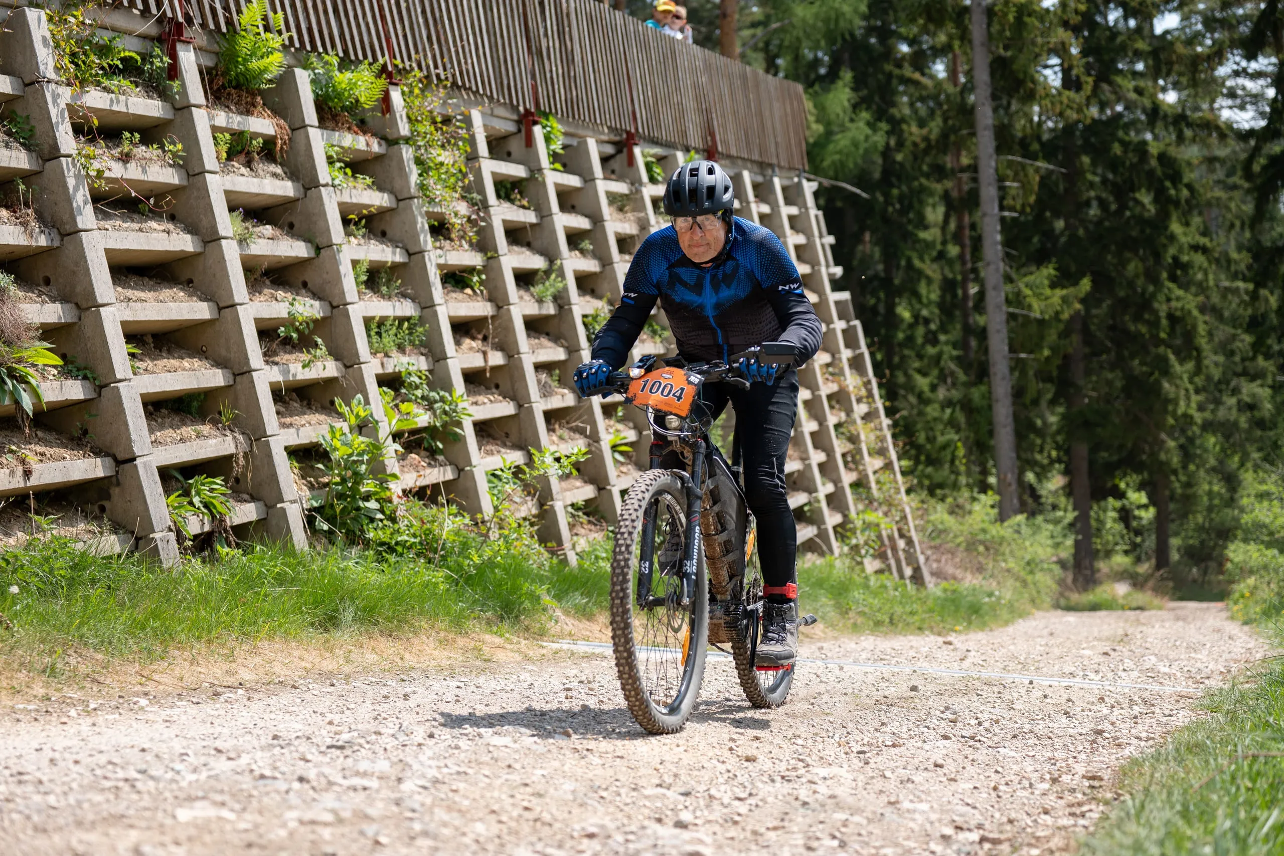 Fahrer auf dem sonnigen Schotterweg vor der begrünten Stützmauer
