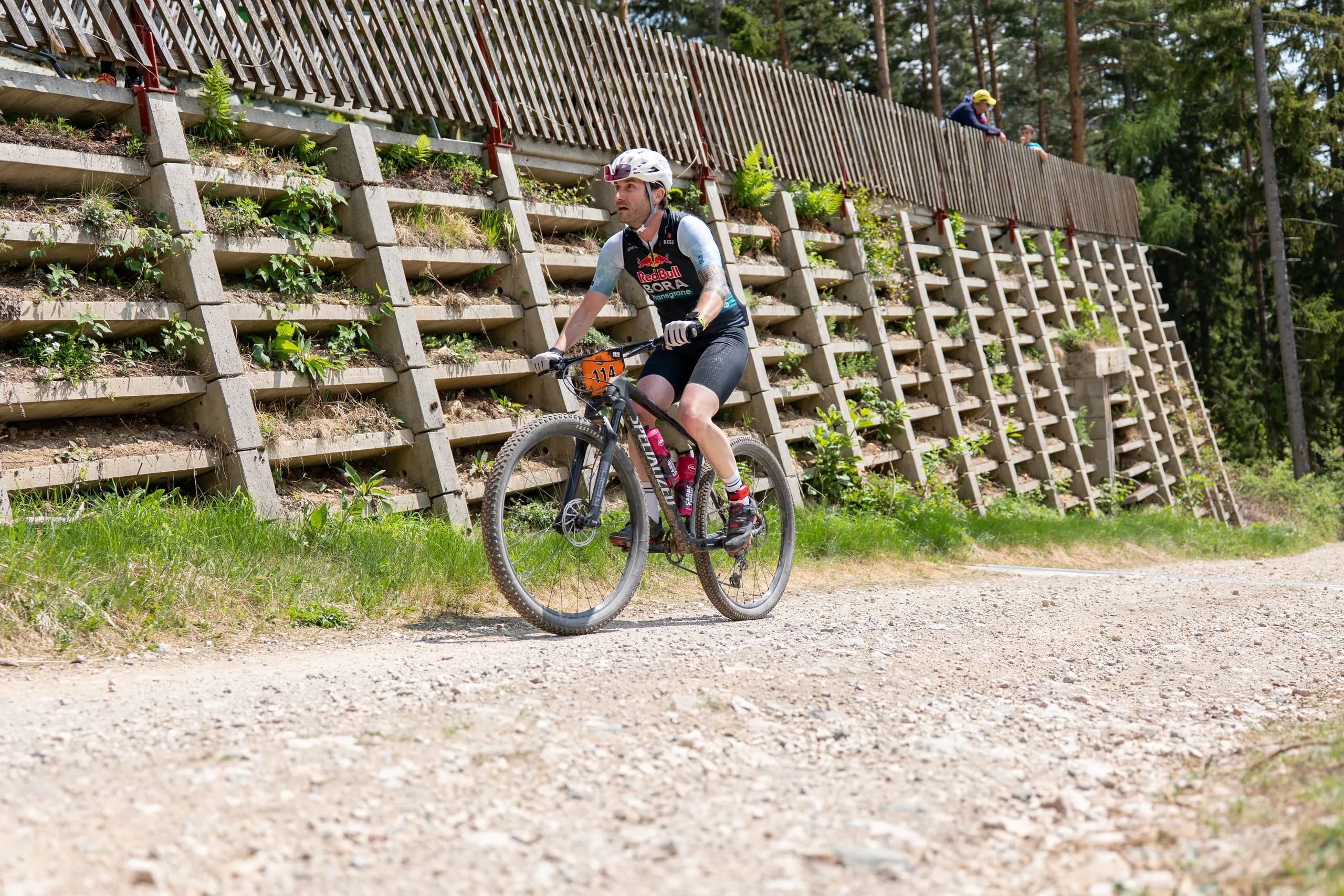 Fahrer auf dem sonnigen Schotterweg vor der begrünten Stützmauer