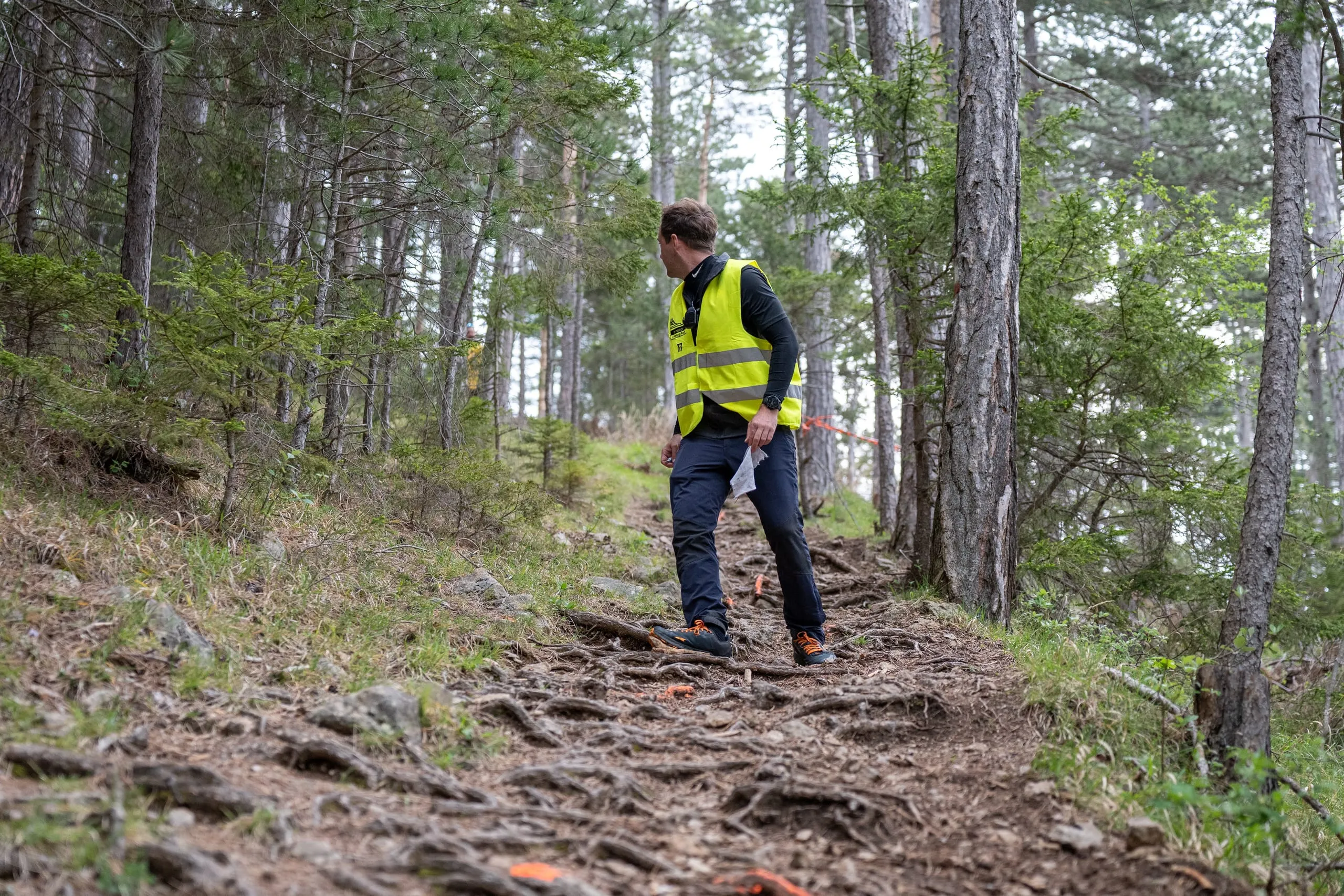 Ein Streckenposten in gelber Warnweste steht auf dem Wurzeltrail im Wald